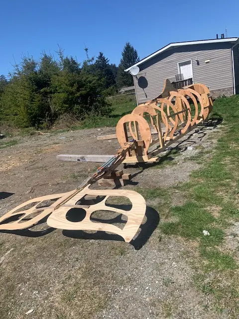 A detailed wooden whale sculpture is positioned on the ground, highlighting its artistic design and natural beauty.